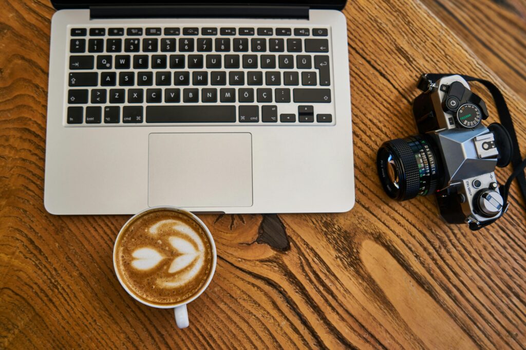 pexels-photo-2347308-2347308 Flat lay of a laptop, cappuccino, and camera on a wooden surface, ideal for work-from-home themes.